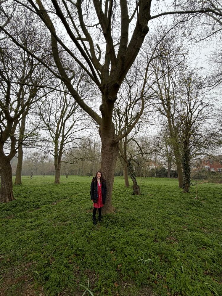 A teenager standing next to a tree in Hall Park