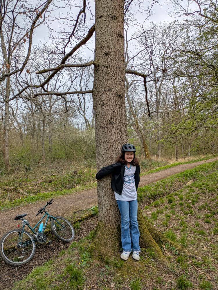 An 11 year old girl with her bike hugging a tree